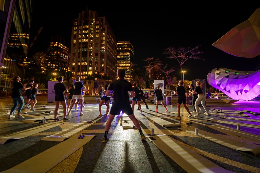 Aula ao ar livre na praça, com o skyline da cidade ao fundo